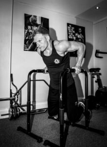 Male personal trainer demonstrates push-up exercise at home gym in Corby.