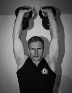 Close-up of a man lifting kettlebells during strength training.