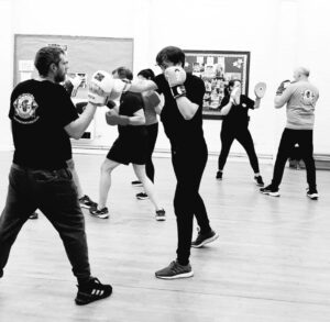 Group boxing class with trainer and participants practicing punching techniques.