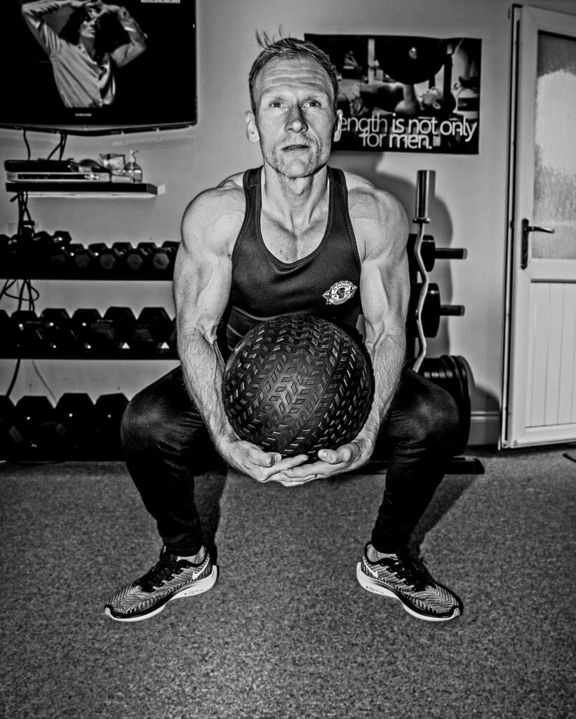 Intense workout with a focused personal trainer lifting a medicine ball.